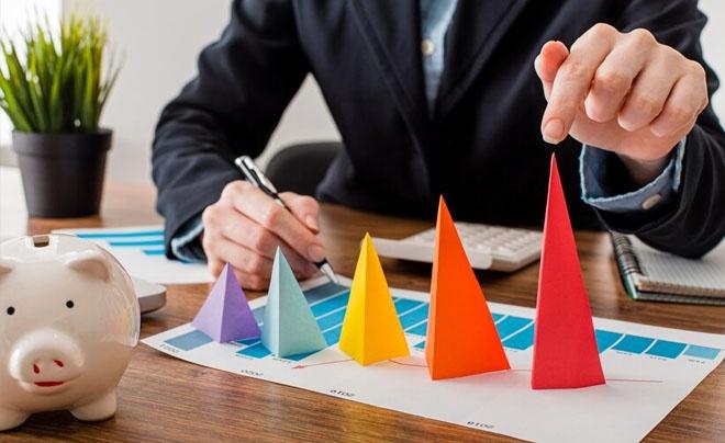 Người cầm bút và chạm vào biểu đồ hình nón màu sắc trên bàn làm việc.