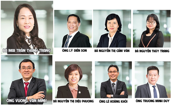 Chín người trong trang phục công sở, đứng trước nền mờ.