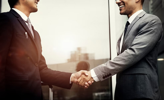 Hai người đàn ông mặc vest đang bắt tay nhau, thể hiện sự hợp tác trong môi trường công sở.