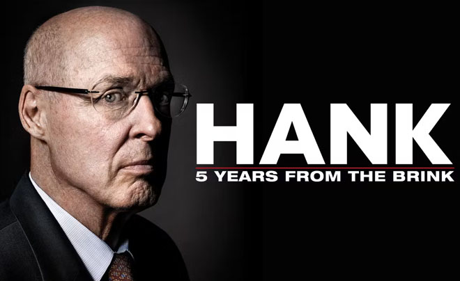 Một người đàn ông đeo kính nhìn nghiêng, nền đen, bên cạnh có dòng chữ "Hank: 5 Years from the Brink".