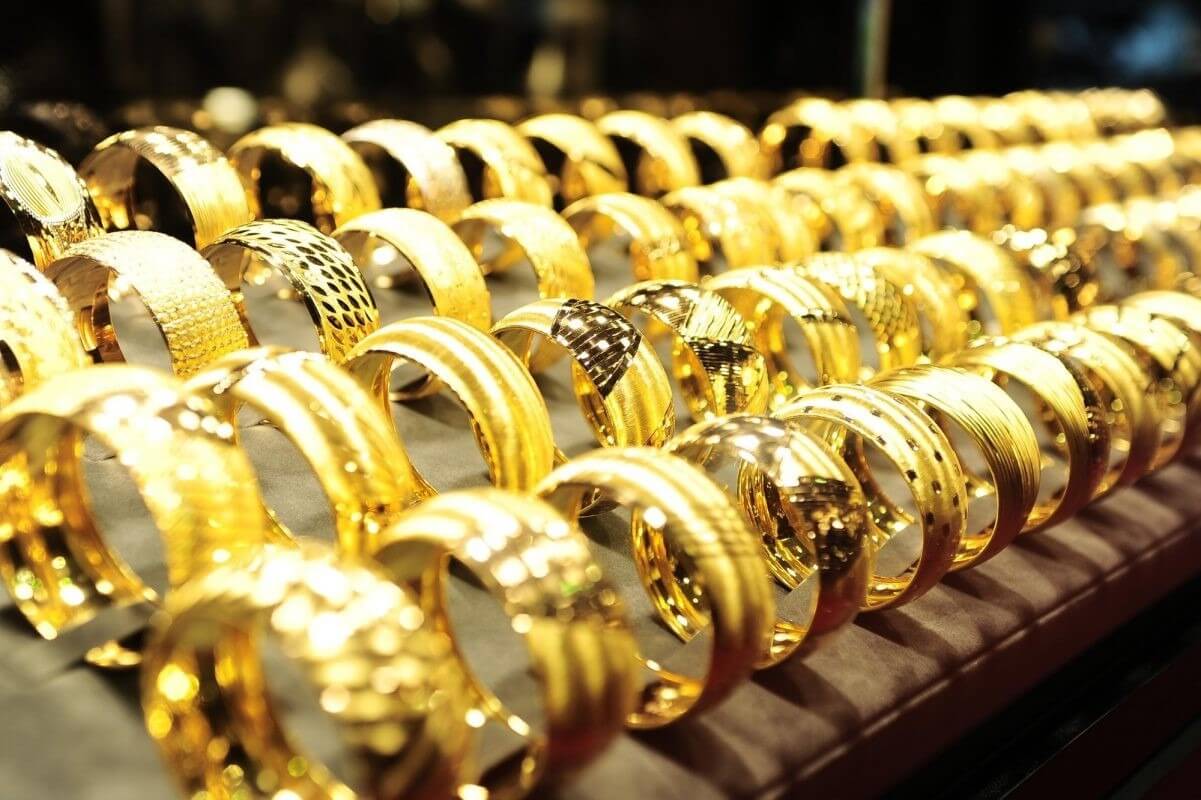 Nhẫn vàng xếp hàng trên nền vải tối, sáng bóng và lấp lánh dưới ánh sáng.
