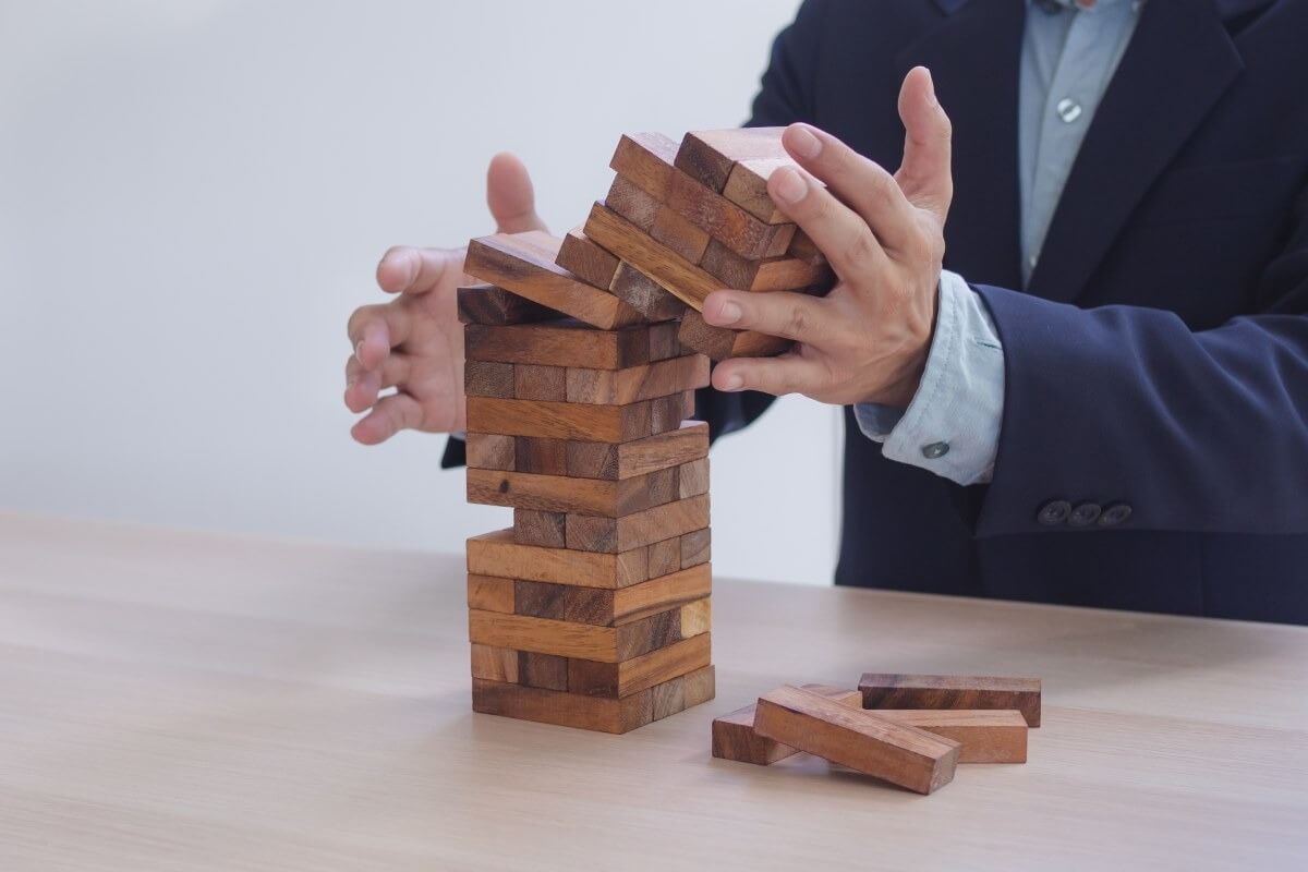 Một người đang chơi trò xếp chồng gỗ, các khối gỗ đang nghiêng và có thể rơi.