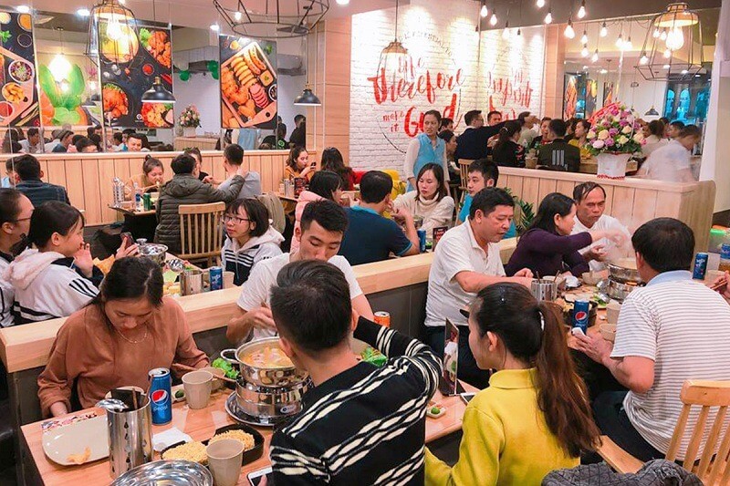 Chiến Lược Đầu Tư Hiệu Quả và An Toàn Với Thu Nhập 10 Triệu 6 Quán ăn đông đúc với nhiều thực khách đang thưởng thức bữa ăn và trò chuyện trong không gian ấm cúng.