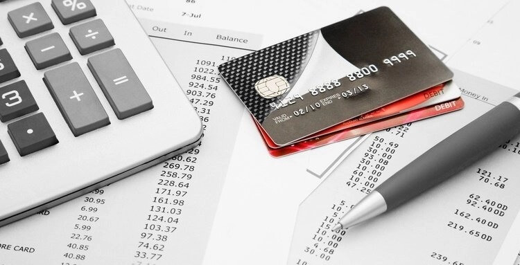 Máy tính, thẻ ngân hàng và bút trên các bảng sao kê tài chính, thể hiện quản lý tài chính cá nhân.