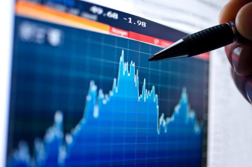 Biểu đồ tài chính hiển thị biến động dữ liệu trên màn hình, với một cây bút chỉ vào.