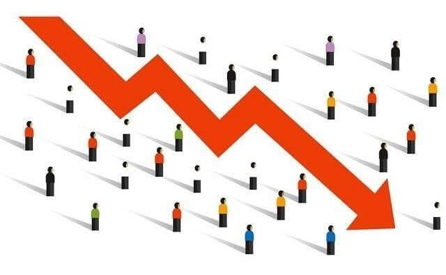 Hình ảnh biểu đồ xu hướng giảm màu đỏ với các hình người nhỏ xung quanh.
