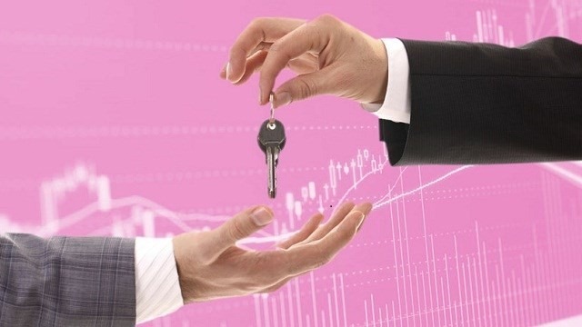 Hai bàn tay trao nhau chìa khóa, nền hồng có đồ thị tài chính.