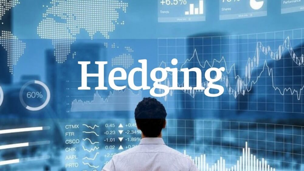 Người đang nhìn biểu đồ tài chính và dòng chữ "Hedging" trên màn hình lớn với bản đồ thế giới.