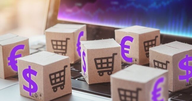 Các hộp giấy nhỏ với biểu tượng giỏ hàng và ký hiệu tiền tệ đặt trên bàn phím laptop.