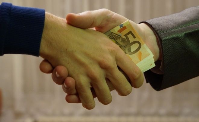 Hai người bắt tay, một người cầm tờ tiền 50 euro trong tay.