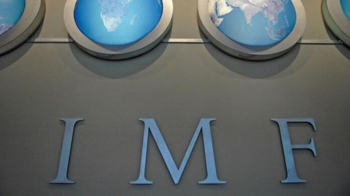 Chữ "IMF" trên tường với hình ảnh các bản đồ thế giới ở phía trên.