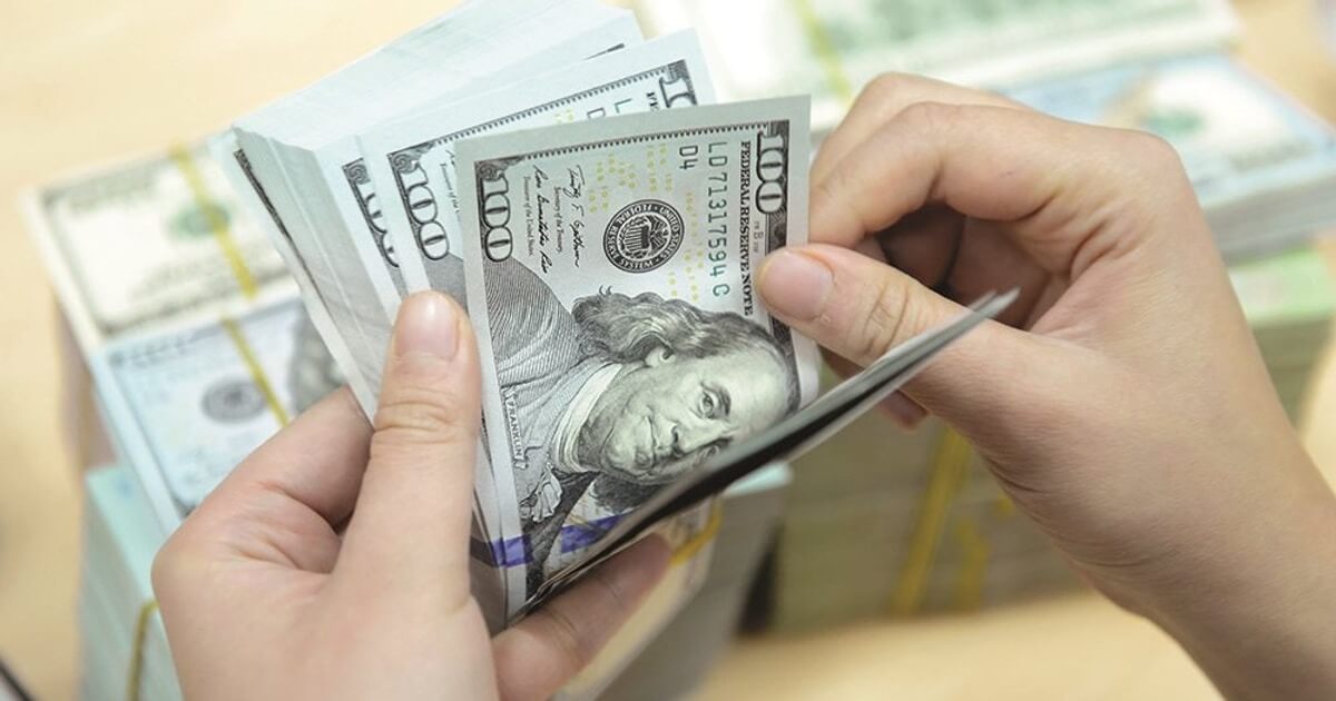 Đôi tay đang đếm nhiều tờ tiền mệnh giá 100 đô la Mỹ.