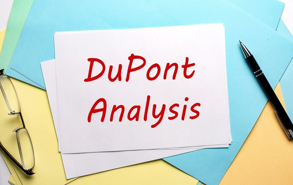 Tờ giấy có chữ "DuPont Analysis" đặt trên mặt bàn cùng với kính và bút.