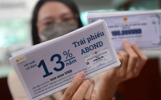 Người đeo khẩu trang cầm phiếu thông tin về trái phiếu với lãi suất cố định 13% mỗi năm.