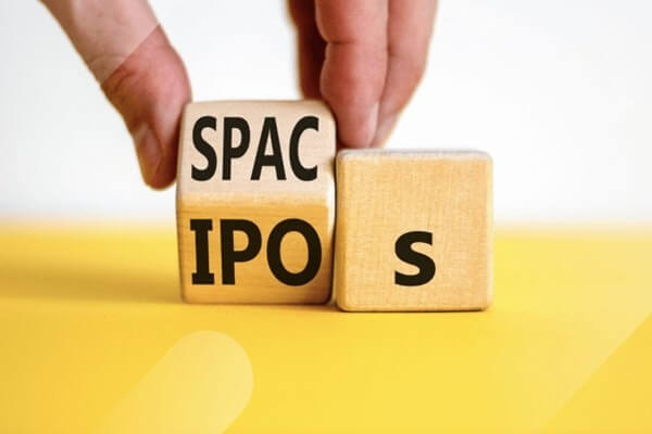 Hai khối gỗ có chữ "SPAC" và "IPOS" trên nền vàng, một tay đang xoay khối gỗ.