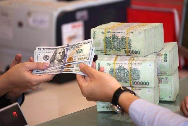 Hai người trao đổi tiền, một bên cầm đô la Mỹ và một bên có tiền Việt Nam trên bàn.