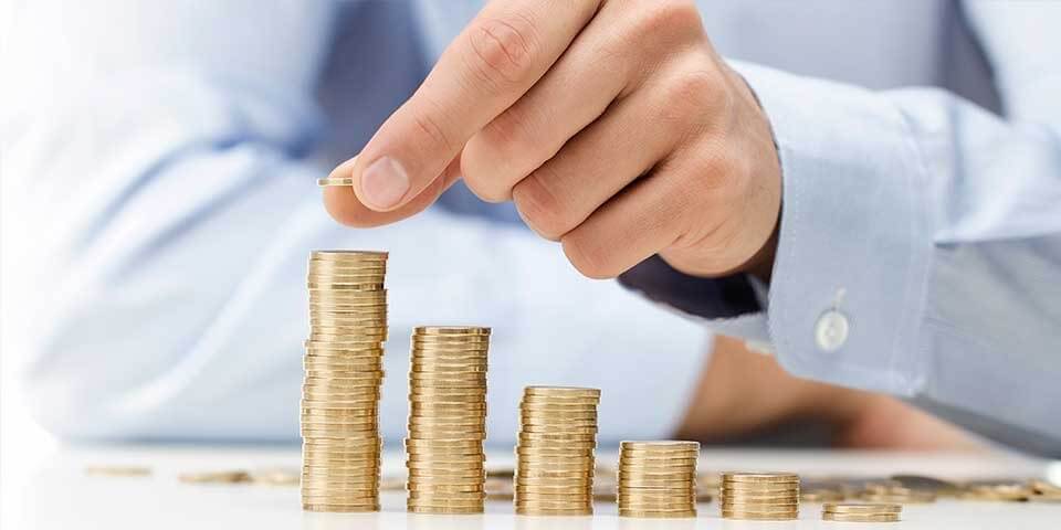 Bàn tay xếp các đồng xu thành bốn cột với chiều cao tăng dần trên bề mặt phẳng.