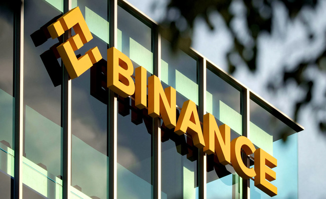 Mặt tiền tòa nhà với logo chữ BINANCE màu vàng trên nền kính và kiến trúc hiện đại.