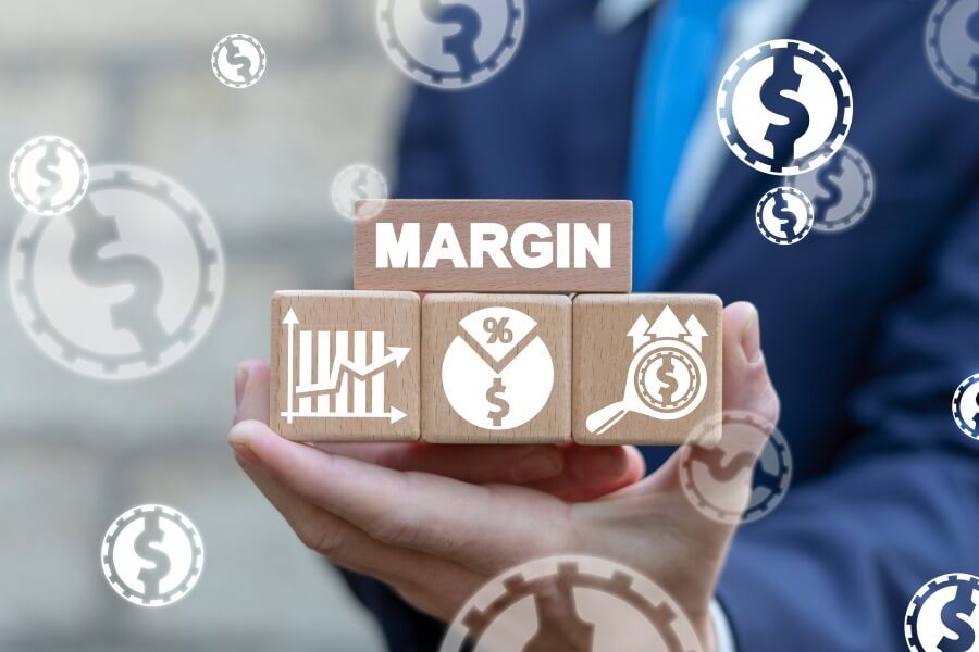 Người cầm các khối gỗ với biểu tượng tài chính và chữ "MARGIN" liên quan đến đầu tư và lợi nhuận.