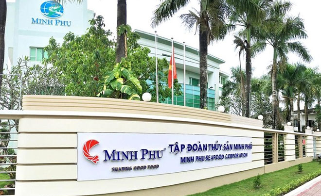 Tòa nhà văn phòng với biển hiệu của một công ty thủy sản, phía trước có cây cối và cờ.