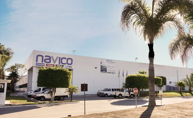 Tòa nhà công ty với logo "navico", xung quanh có cây cọ và xe ô tô đậu phía trước.