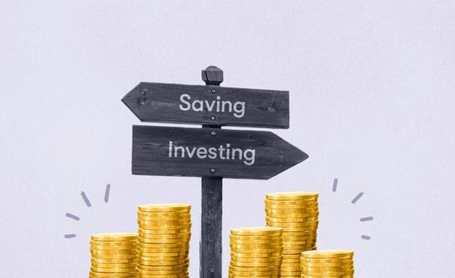 Biển chỉ dẫn với hai hướng "Saving" và "Investing", bên dưới là các chồng xu vàng.