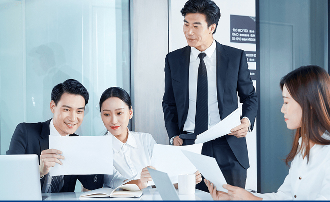 Nhóm người trong trang phục công sở đang thảo luận và xem xét tài liệu trong phòng họp.