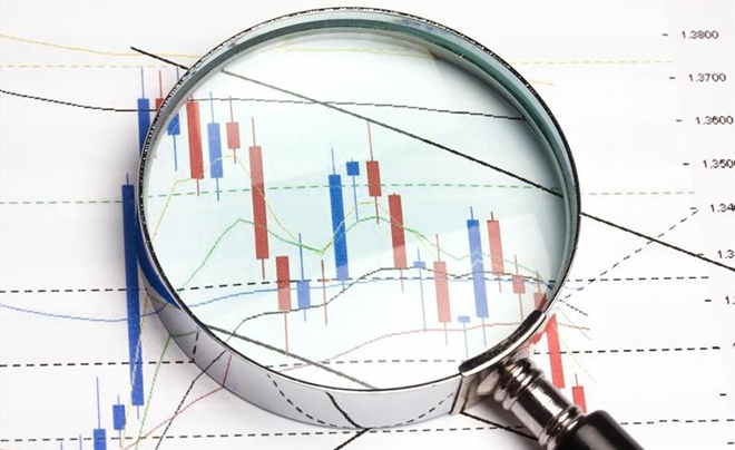 Kính lúp phóng to biểu đồ nến trên giấy, biểu thị biến động giá trong thị trường tài chính.