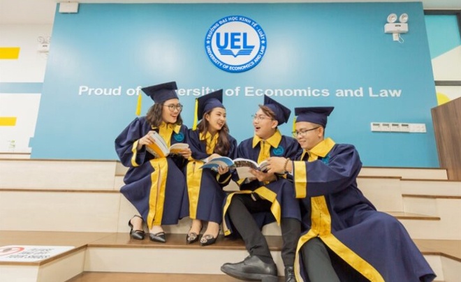 Bốn sinh viên mặc lễ phục tốt nghiệp ngồi trên bậc thang, cầm sách, cười nói trong khuôn viên trường đại học.