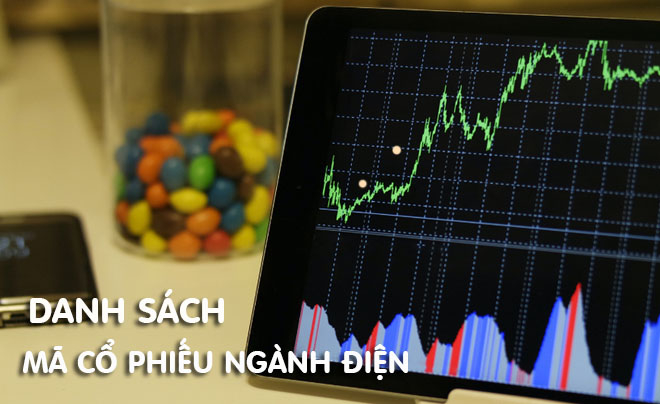 Máy tính bảng hiển thị biểu đồ giá cổ phiếu, bên cạnh là hộp kẹo nhiều màu và điện thoại di động.