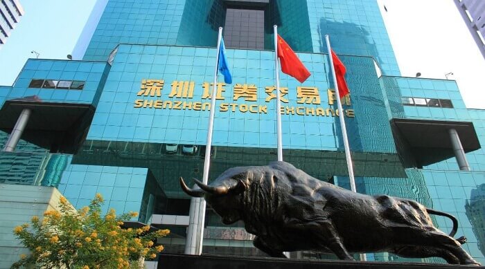Tòa nhà với tượng bò và cột cờ phía trước, biển hiệu ghi "Shenzhen Stock Exchange".