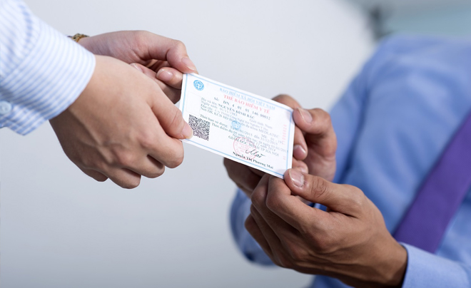 Hai người đang trao đổi thẻ, một người đưa thẻ còn người kia nhận thẻ trong bối cảnh văn phòng.