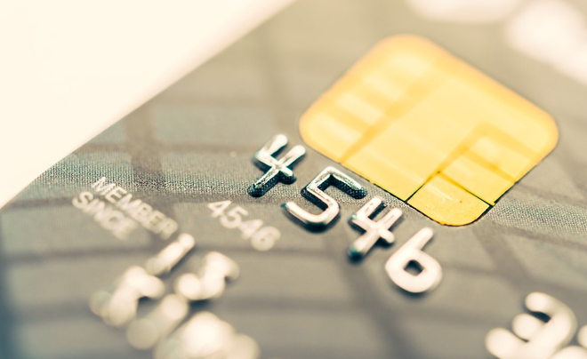 Gần cận thẻ tín dụng với con chip và số nổi, ánh sáng chiếu qua bề mặt.