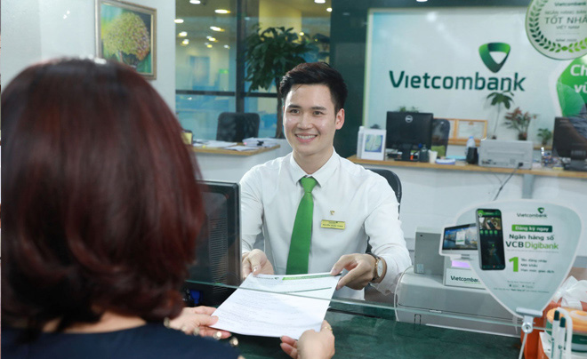 Nhân viên ngân hàng đang giao dịch với khách hàng tại quầy giao dịch Vietcombank.