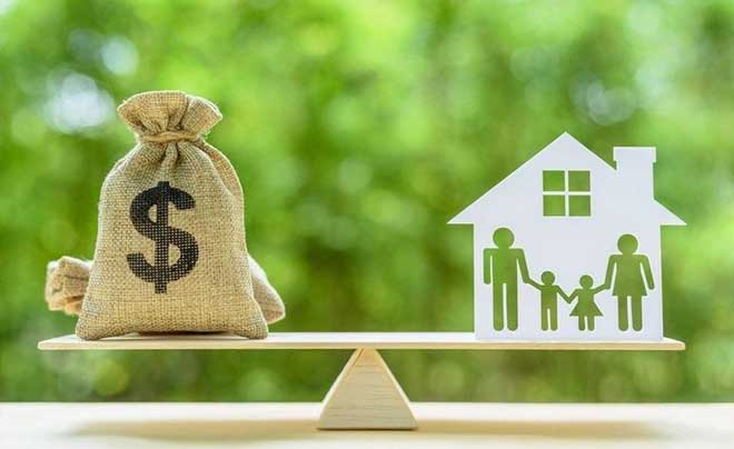 Túi tiền và mô hình ngôi nhà với gia đình trên bập bênh, tượng trưng cho sự cân bằng tài chính và cuộc sống.
