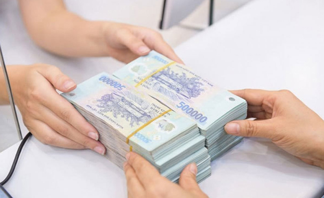 Hai người đang trao đổi xấp tiền Việt Nam đồng mệnh giá 500.000 trên bàn trắng.