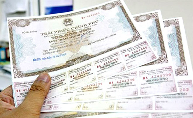 Người cầm nhiều tờ trái phiếu chính phủ Việt Nam, mệnh giá và thông tin chi tiết hiển thị rõ ràng trên mỗi tờ.