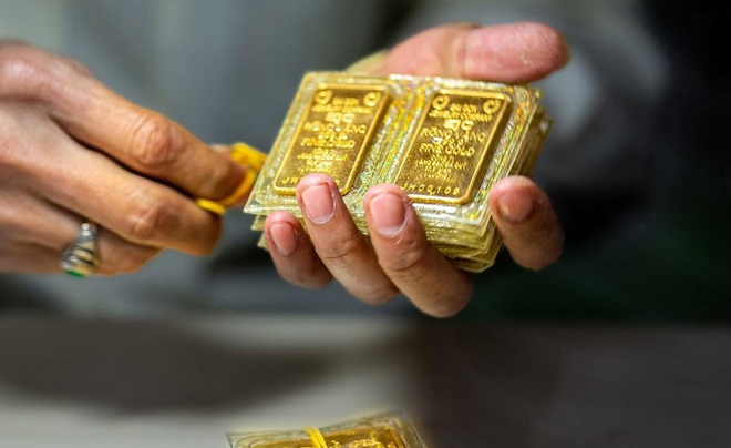 Người đang cầm nhiều thỏi vàng nhỏ gói trong bao bì nhựa trong suốt.