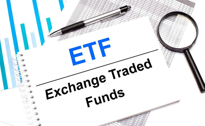 Văn bản "ETF Exchange Traded Funds" trên giấy, cùng với bút và biểu đồ tài chính.