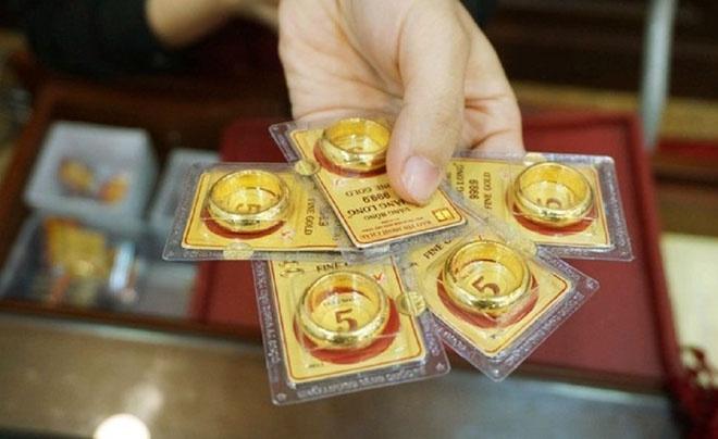 Tay cầm bốn miếng vàng miếng trong hộp nhựa, mỗi miếng có một vòng tròn vàng bên trên.
