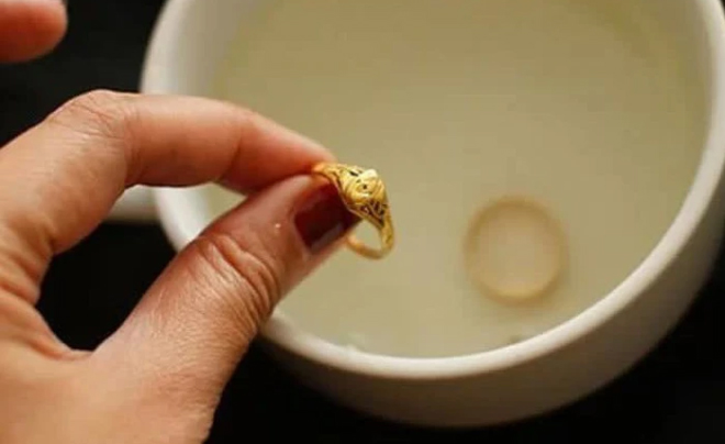 Người cầm nhẫn vàng gần một bát nước, bên trong có thể thấy một chiếc nhẫn khác.