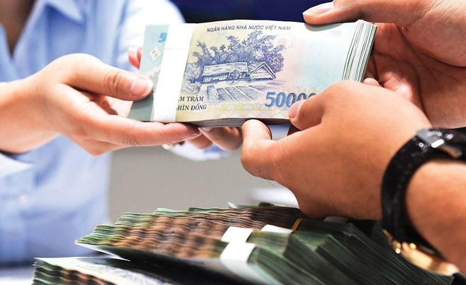 Hai người trao đổi cọc tiền Việt Nam, mệnh giá 500 nghìn đồng, trong một không gian nội thất.