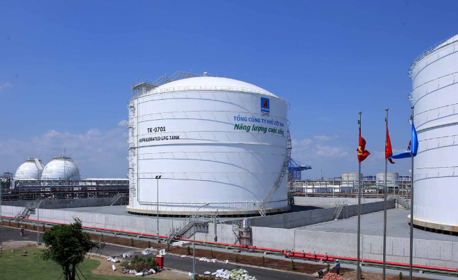 C&aacute;c bồn chứa lớn v&agrave; cơ sở hạ tầng c&ocirc;ng nghiệp với cờ v&agrave; đường ống, nền trời trong xanh.