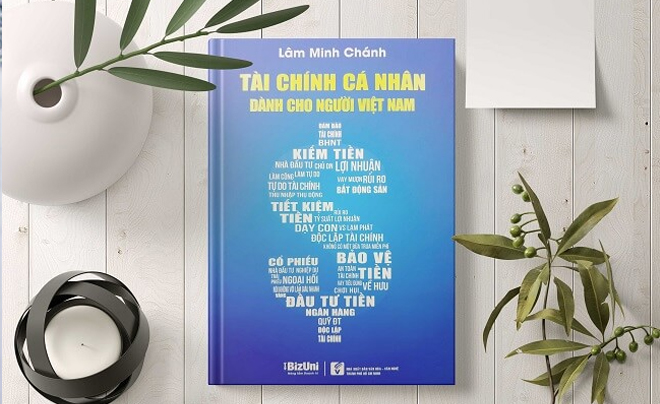 Bìa sách màu xanh với tiêu đề về tài chính cá nhân, xung quanh có cây xanh và nến trang trí trên bàn gỗ trắng.