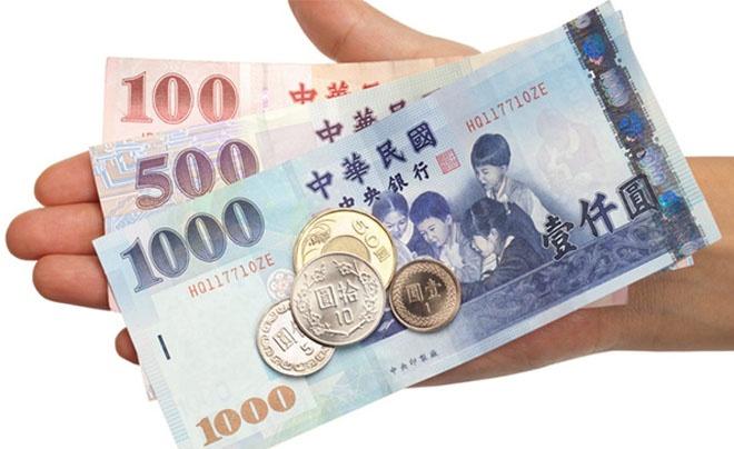 Một bàn tay đang cầm các tờ tiền và đồng xu Đài Loan, gồm mệnh giá 100, 500, 1000 và các đồng xu khác nhau.