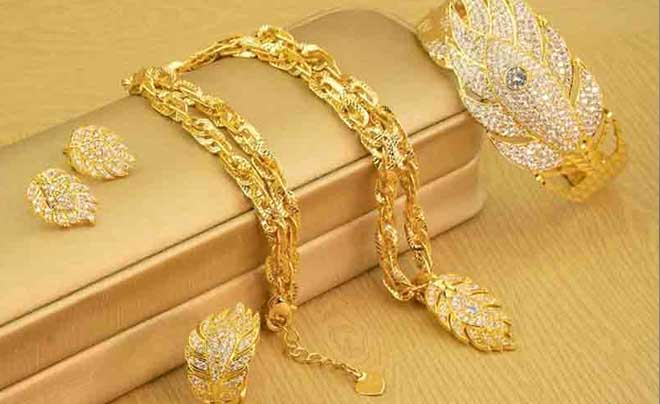 Bộ trang sức vàng gồm vòng cổ, vòng tay, nhẫn và hoa tai, thiết kế họa tiết lá, đính đá lấp lánh.