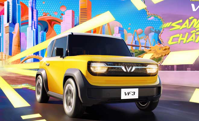 Xe ô tô màu vàng đang di chuyển trên đường với nền thành phố và ánh sáng đa sắc phía sau.