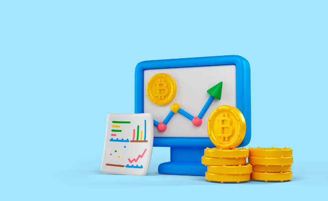 Biểu đồ và biểu tượng Bitcoin trên màn hình máy tính, cạnh đó là các đồng xu vàng và biểu đồ giấy.